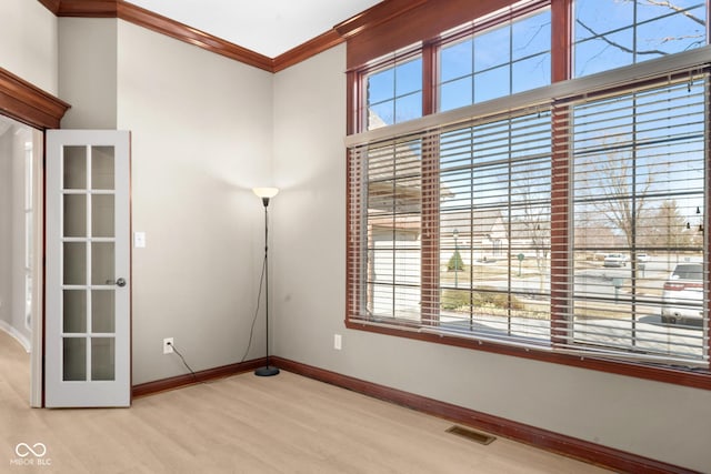 spare room with baseboards, visible vents, crown molding, and wood finished floors