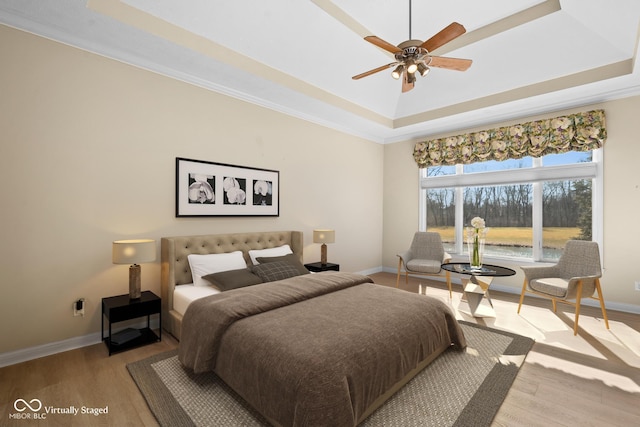 bedroom featuring a tray ceiling, wood finished floors, and baseboards