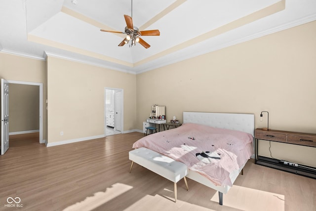 bedroom with a raised ceiling, ornamental molding, a ceiling fan, wood finished floors, and baseboards