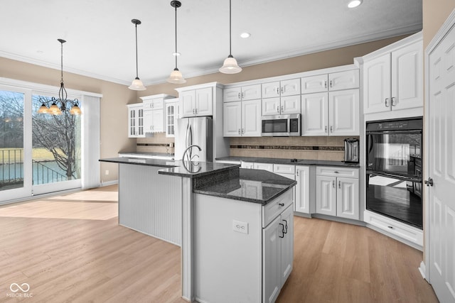 kitchen featuring stainless steel appliances, light wood-type flooring, crown molding, and backsplash