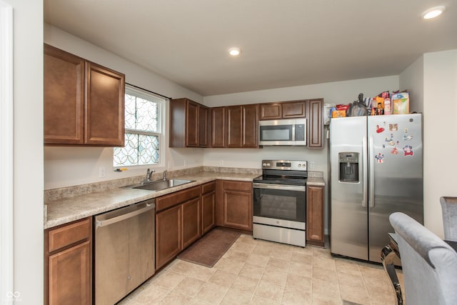 kitchen featuring stainless steel appliances, a sink, light countertops, and recessed lighting