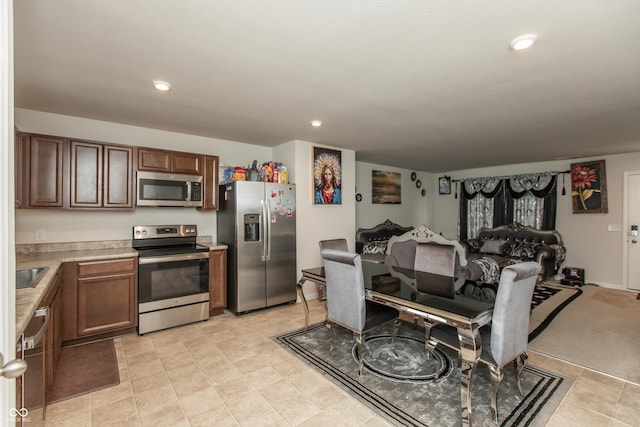 kitchen featuring stainless steel appliances, recessed lighting, light countertops, and a sink