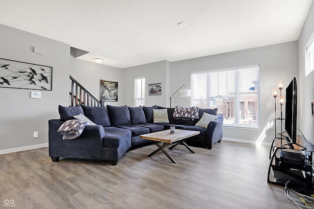 living area featuring stairway, baseboards, a textured ceiling, and wood finished floors