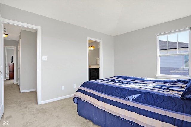 bedroom featuring connected bathroom, baseboards, and light carpet