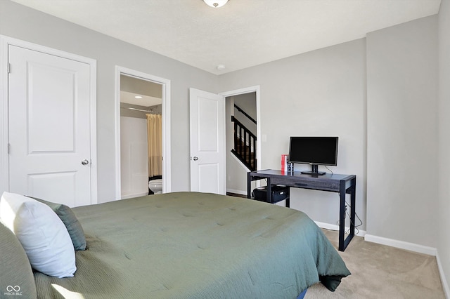 bedroom featuring connected bathroom, baseboards, and light colored carpet