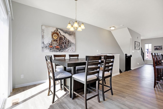 dining room with baseboards, wood finished floors, visible vents, and a chandelier