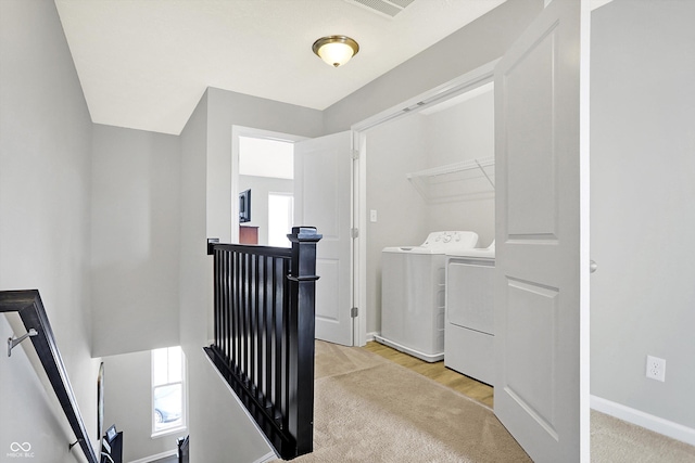 interior space with light carpet, an upstairs landing, baseboards, and washer and clothes dryer