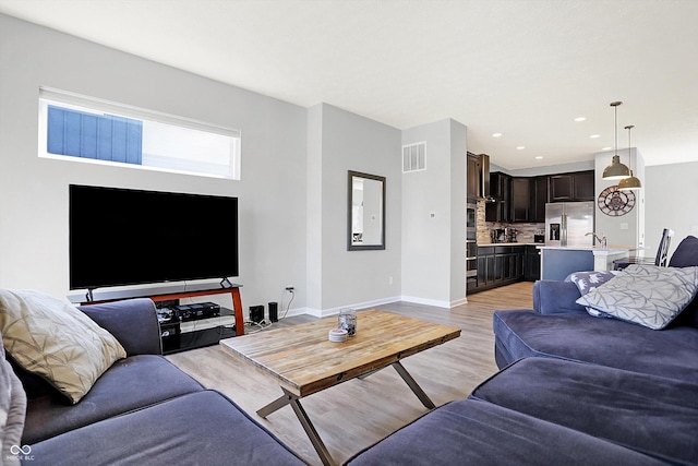 living area with recessed lighting, light wood-style floors, visible vents, and baseboards