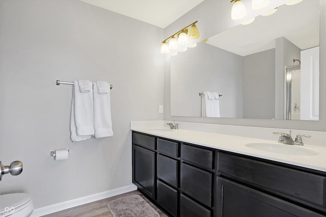 full bath featuring toilet, wood finished floors, baseboards, and a sink