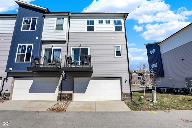 exterior space with a balcony, an attached garage, board and batten siding, and driveway