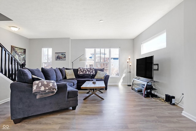 living room with stairway, wood finished floors, baseboards, and a textured ceiling