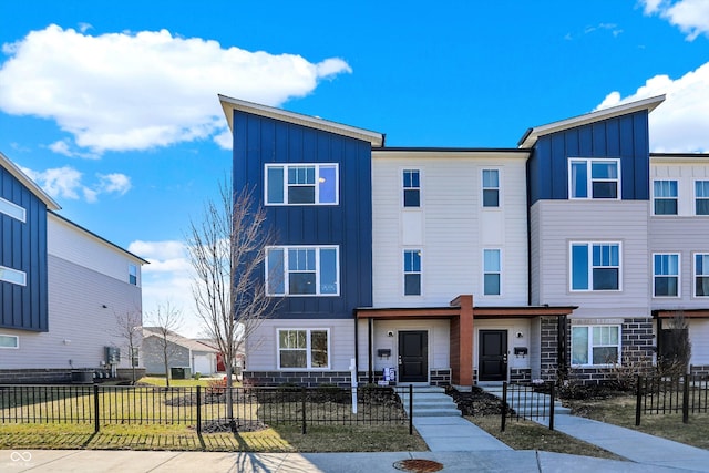 multi unit property featuring a fenced front yard, stone siding, and board and batten siding