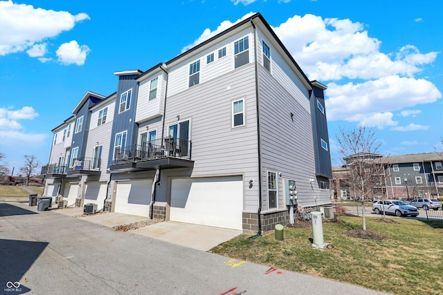 view of side of home with a garage, central air condition unit, a residential view, and concrete driveway