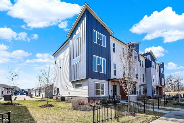 exterior space featuring a residential view, central AC unit, board and batten siding, and fence