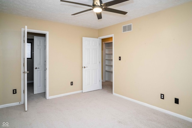 unfurnished bedroom with visible vents, light carpet, baseboards, and a textured ceiling