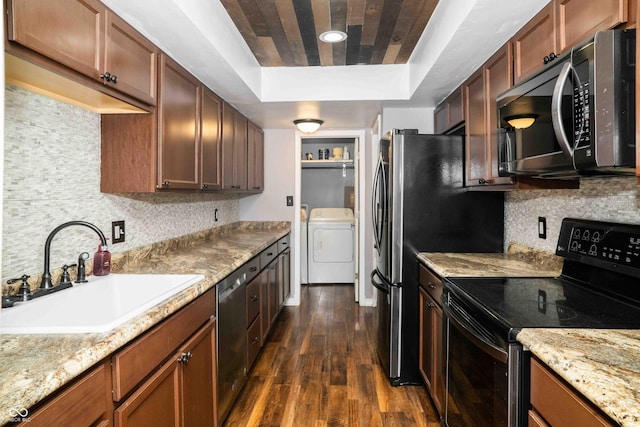 kitchen featuring tasteful backsplash, dark wood finished floors, appliances with stainless steel finishes, a tray ceiling, and a sink