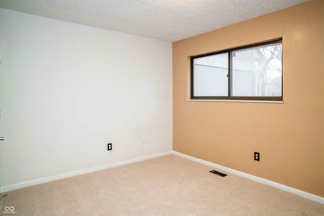 unfurnished room featuring carpet, visible vents, a textured ceiling, and baseboards