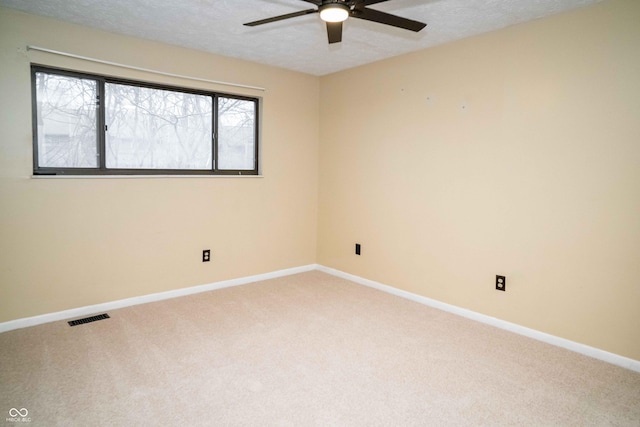 carpeted spare room featuring a textured ceiling, ceiling fan, visible vents, and baseboards