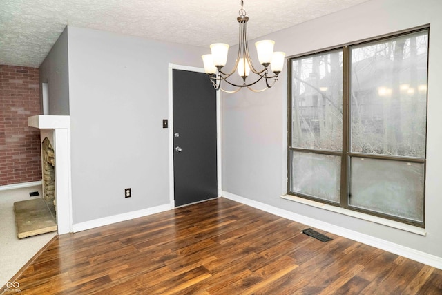 interior space featuring a notable chandelier, a textured ceiling, visible vents, and wood finished floors