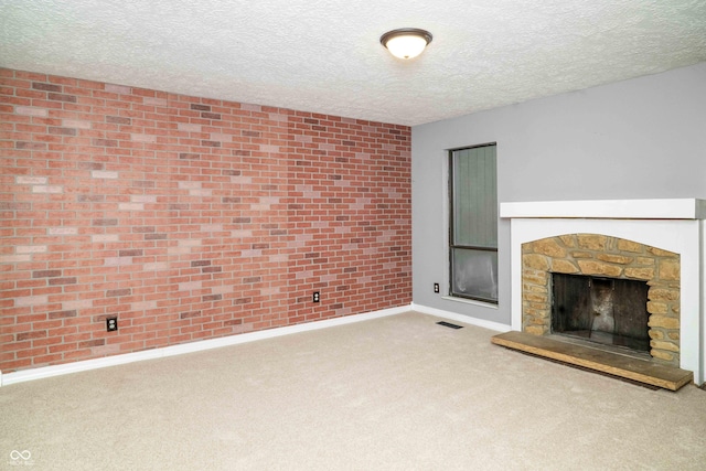 unfurnished living room with carpet floors, a fireplace, visible vents, a textured ceiling, and baseboards