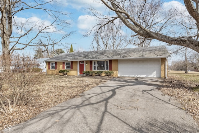 ranch-style home featuring an attached garage, aphalt driveway, and brick siding