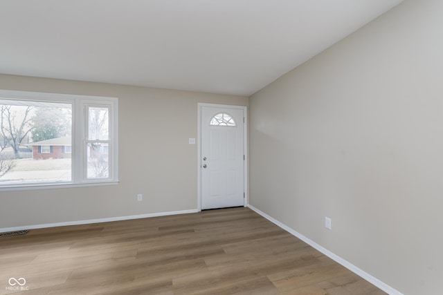 foyer with lofted ceiling, visible vents, light wood-style flooring, and baseboards