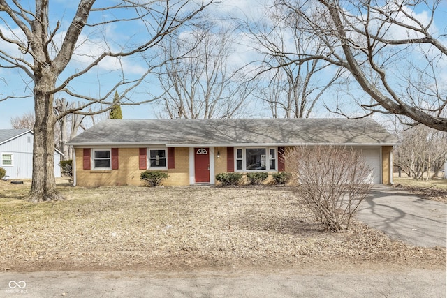 single story home featuring driveway, brick siding, and an attached garage