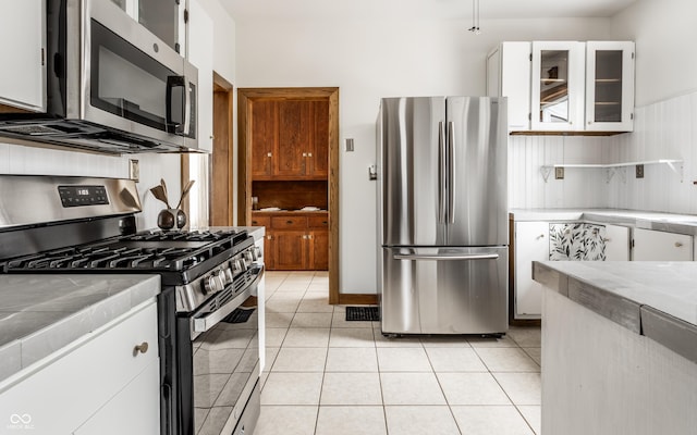 kitchen with tile countertops, stainless steel appliances, and light tile patterned floors