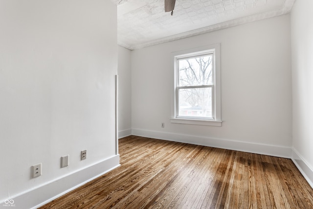 spare room with wood-type flooring and baseboards