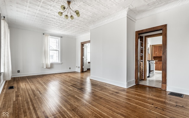 spare room featuring an ornate ceiling, visible vents, wood-type flooring, and baseboards