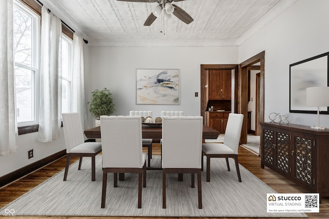 dining space featuring an ornate ceiling, a wealth of natural light, baseboards, and wood finished floors