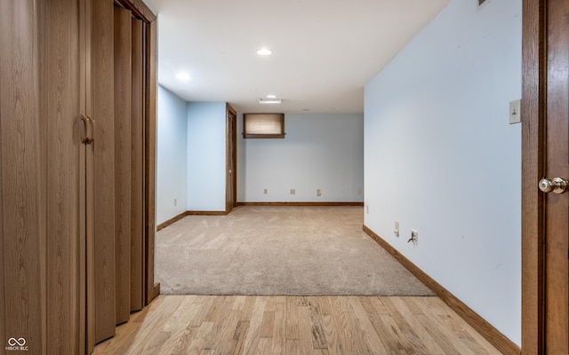 interior space with light wood-style floors, light colored carpet, and baseboards