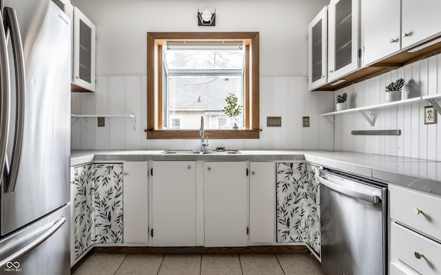 kitchen with light tile patterned floors, stainless steel appliances, light countertops, open shelves, and a sink