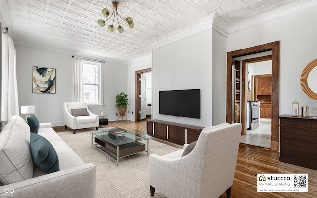 living room with a notable chandelier, an ornate ceiling, baseboards, and wood finished floors