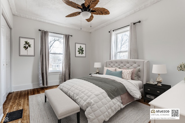 bedroom featuring a ceiling fan, multiple windows, baseboards, and wood finished floors