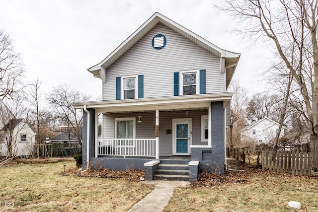 view of front facade featuring a front yard, covered porch, and fence