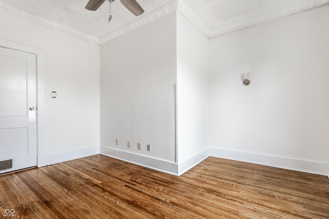 empty room with a ceiling fan, crown molding, baseboards, and wood finished floors