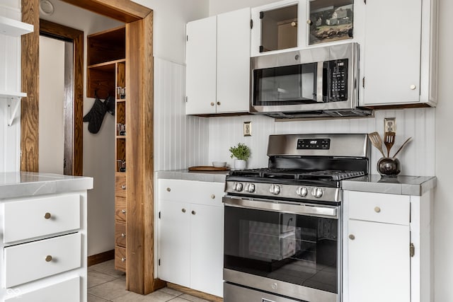 kitchen featuring open shelves, light tile patterned floors, decorative backsplash, appliances with stainless steel finishes, and white cabinetry