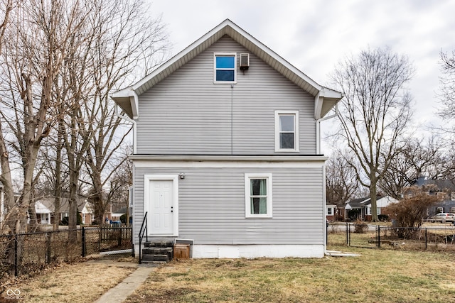 rear view of property featuring entry steps, a lawn, and a fenced backyard