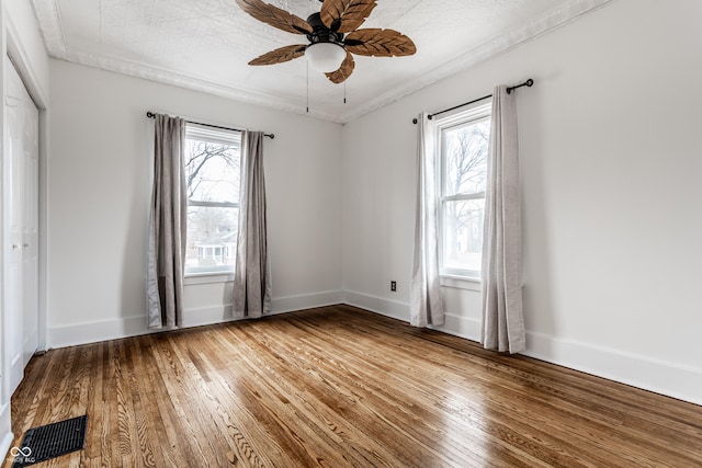 empty room with a ceiling fan, a healthy amount of sunlight, and hardwood / wood-style floors