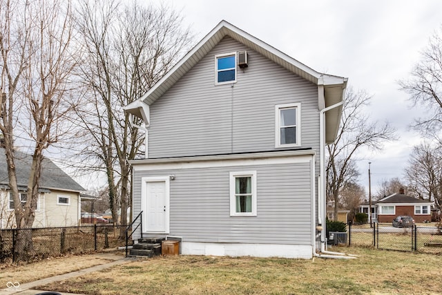 rear view of house featuring entry steps, cooling unit, fence, and a lawn