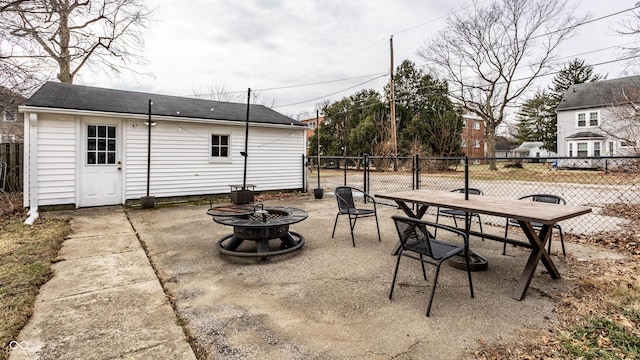 view of patio / terrace featuring an outdoor fire pit, fence, and an outdoor structure