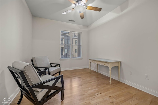 sitting room with light wood-style flooring, visible vents, ceiling fan, and baseboards