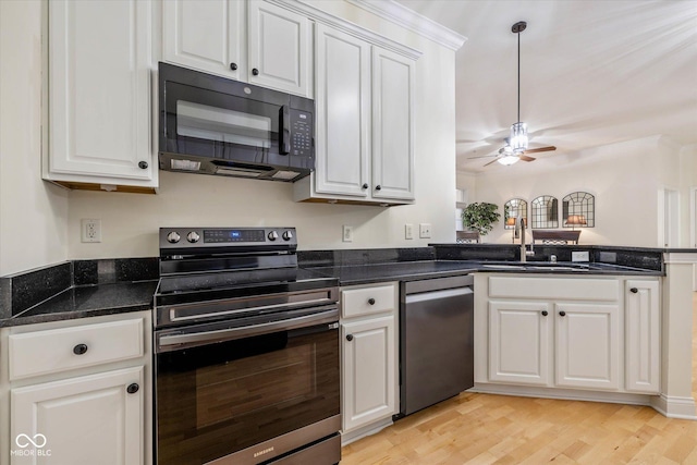 kitchen featuring white cabinets, light wood-style flooring, appliances with stainless steel finishes, a peninsula, and a sink