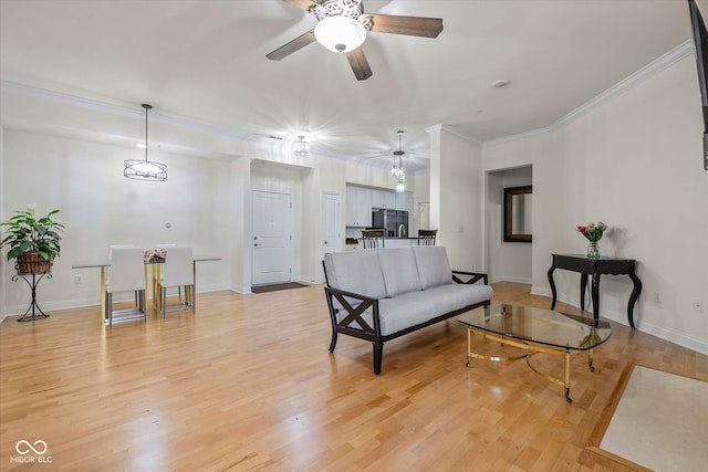 living area with baseboards, light wood finished floors, and crown molding