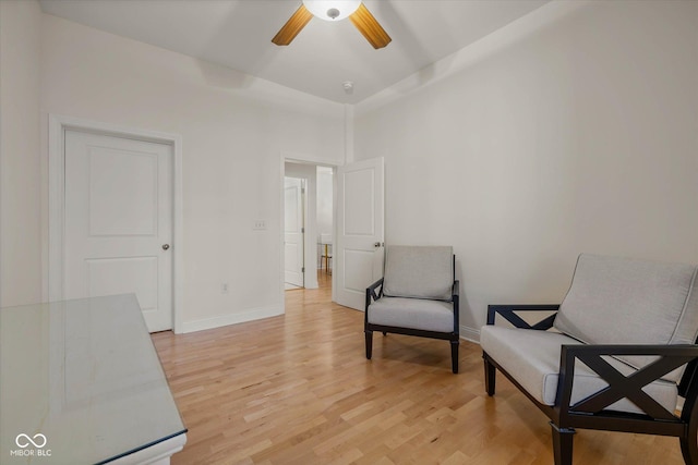 living area with baseboards, ceiling fan, and light wood-style floors