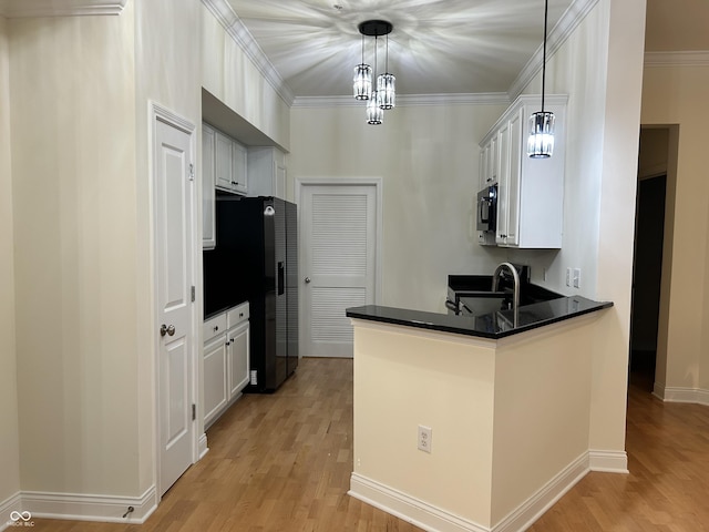 355 E Ohio St E Unit 206, Indianapolis, IN 46204 - kitchen with dark countertops, a peninsula, light wood-style floors, and crown molding