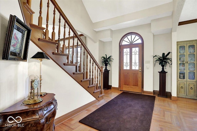 foyer with vaulted ceiling, stairway, and baseboards