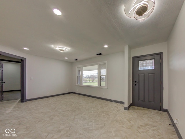 foyer entrance featuring a textured ceiling, recessed lighting, visible vents, and baseboards