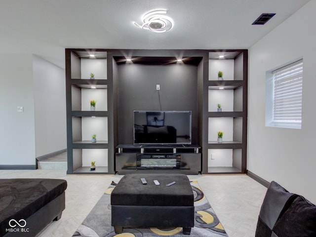 living area with built in shelves, visible vents, and baseboards